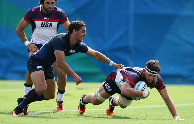 A heavily bearded U.S. player stretches, with help from a friend, during the Mens Rugby Sevens Pool A match between the U.S. and Argentina. Image via Getty.